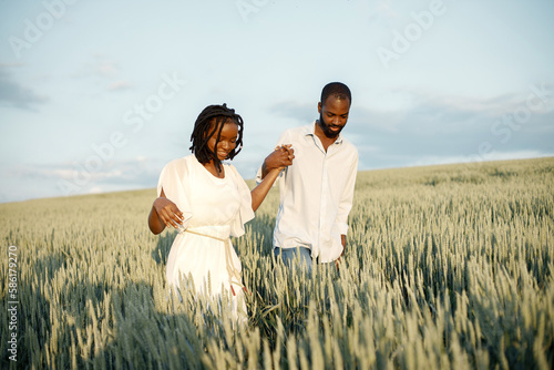 Young black couple walking through green field
