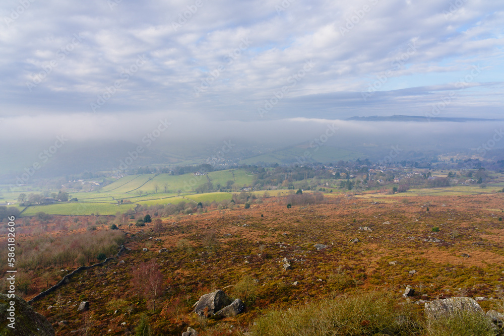 Weak winter sunlight cuts through dense fog in Hope Valley, Derbyshire.