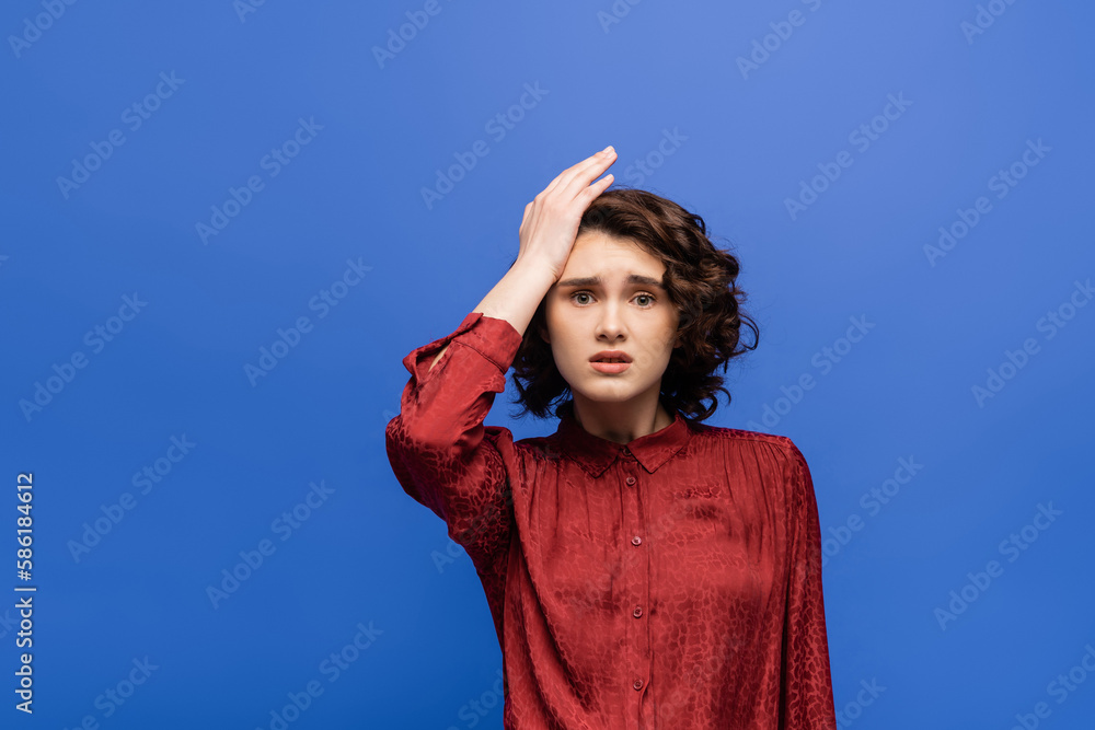 stressed language teacher touching head while looking at camera isolated on blue. stressed language teacher touching head while looking at camera isolated on blue.