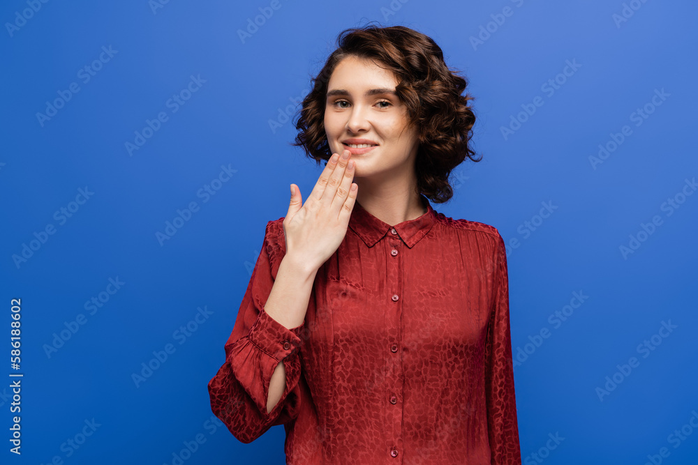 smiling teacher showing thank you gesture on sign language isolated on blue. smiling teacher showing thank you gesture on sign language isolated on blue.
