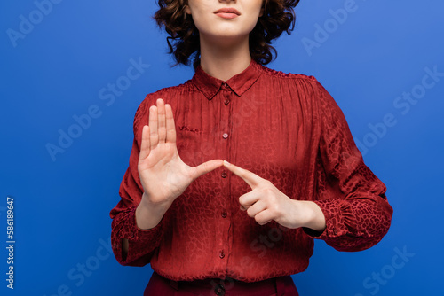 partial view of teacher in burgundy blouse using sign language isolated on blue. photo