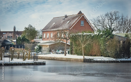 Piękna śnieżna zima w Niderlandach. Spokojny wiejski krajobraz z wiejskim domem i kanałem.