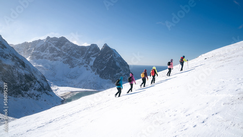 Process of hiking in Northern Norway, Lofoten Islands, Nordland, on the way to Ryten mountain and Kvalvika beach, with a groups of hikers, and mountains around, sunny winter day photo