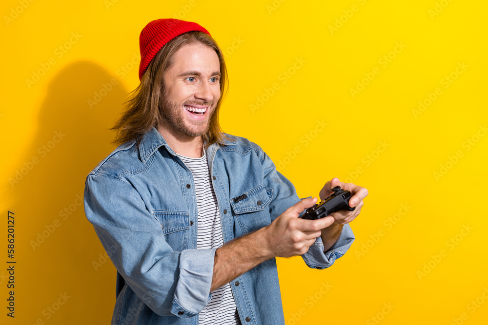 Photo of attractive funny guy dressed jeans shirt enjoying playstation empty space isolated yellow color background Photo of attractive funny guy dressed jeans shirt enjoying playstation empty space isolated yellow color background