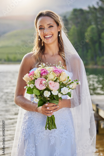 Portrait  bride and smile with flower bouquet at lake  nature and celebration of commitment  love and marriage. Happy woman  wedding and flowers outdoor for bridal fashion  style and excited ceremony
