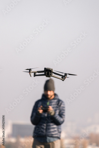 Man with a beard and unfocused pilots his gray drone outside of Berlin