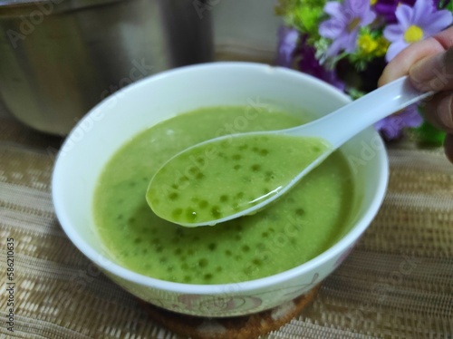 Green tapioca pearl porridge with coconut milk, served in a white bowl. Ready to eat.