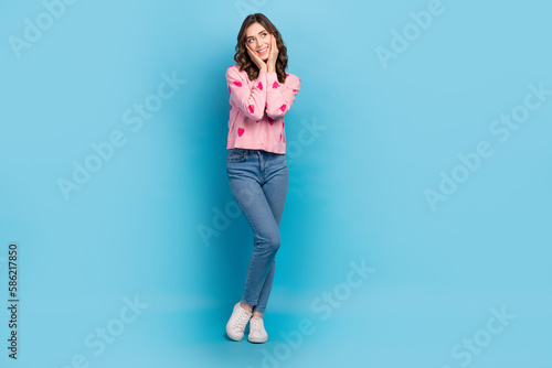 Full length photo of sweet dreamy woman wear pink cardigan arms cheeks looking emtpy space isolated blue color background