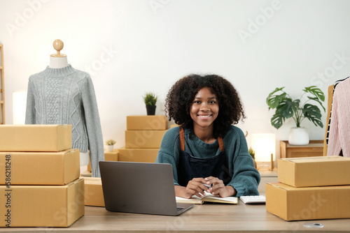 American African entrepreneur smile and checking online order. Successful SME entrepreneur concept