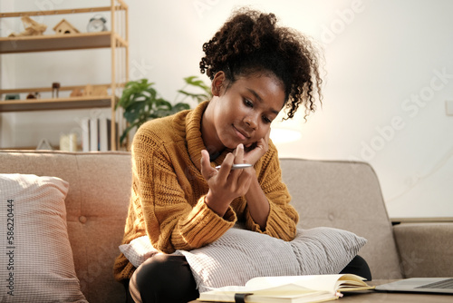 Full length portrait of young African-American woman working from home while sitting on floor in comfortable setting, copy space