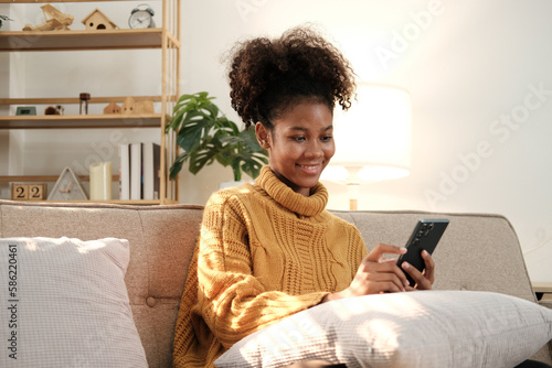 Woman using smartphone at home. Mixed race girl looking at mobile phone. Communication, leisure, connection, mobile apps, technology, learning, web chat, lifestyle concept