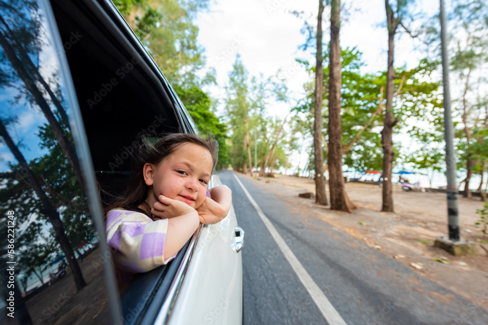 Little Asian child girl sitting in the car with pull her face and hand out of the window in summer sunny day. Happy Asian family enjoy and fun together with outdoor lifestyle on road trip vacation. Little Asian child girl sitting in the car with pull her face and hand out of the window in summer sunny day. Happy Asian family enjoy and fun together with outdoor lifestyle on road trip vacation.
