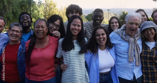 Group of multigenerational people smiling in front of camera - Multiracial friends with different ages having fun together at city park 