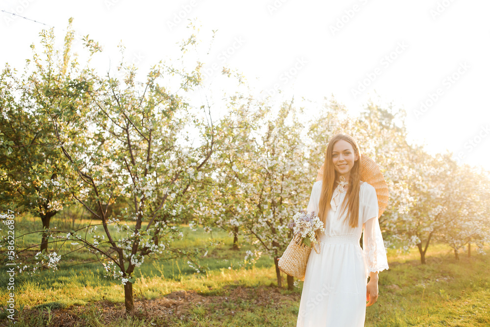Amazing young woman in a straw hat posing in a garden of flowering trees in spring. Amazing young woman in a straw hat posing in a garden of flowering trees in spring.