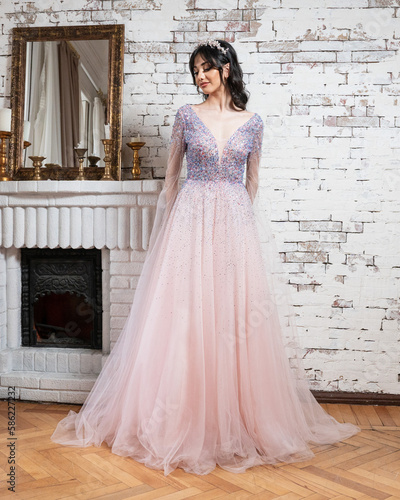 Woman in a pink dress standing in front of a brick wall