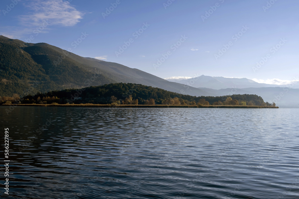 Greece, Pamvotis Lake, Ioannina city Epirus. Giannena nisaki, dark calm water, blue sky background.