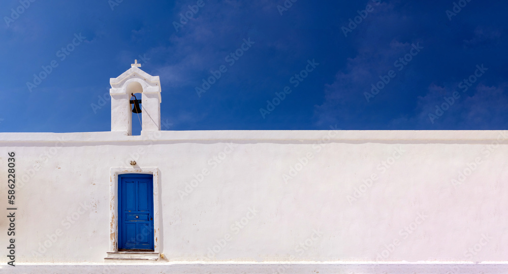 Cyclades, Greece. Small white church and belfry against blue sky, sunny day