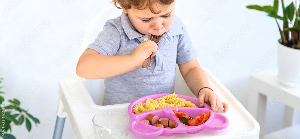 The child eats pasta and vegetables. Selective focus. The child eats pasta and vegetables. Selective focus.