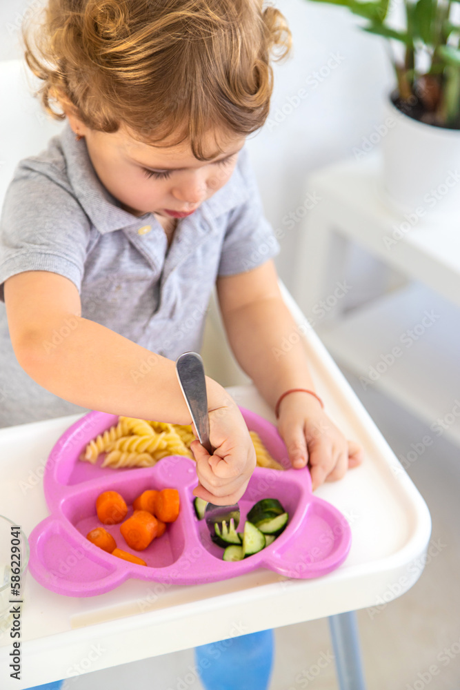 The child eats pasta and vegetables. Selective focus. The child eats pasta and vegetables. Selective focus.