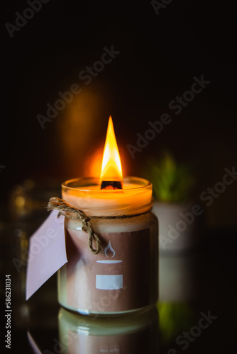 scented burning candle in a glass jar on a black background