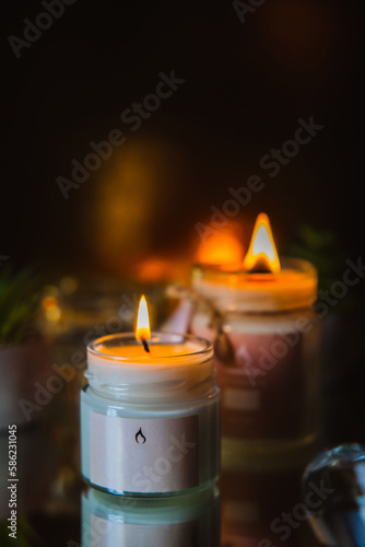 scented burning candle in a glass jar on a black background
