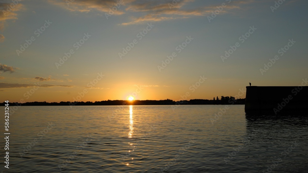 Sunset behind horizon with reflection and glitter on lake