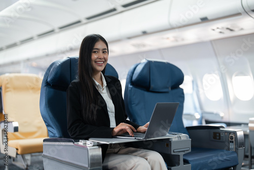Female passenger sitting on plane while working on laptop computer with simulated space using on board wireless connection