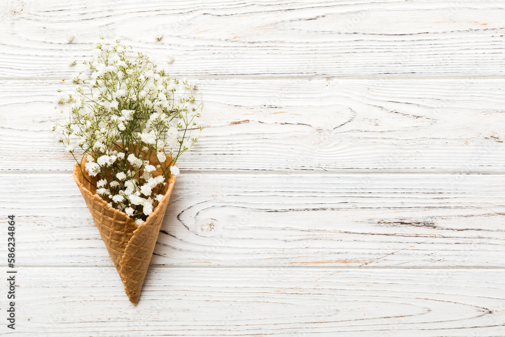 Waffle cone with beautiful gypsophila flowers on color background. summer concept. Copy space top view