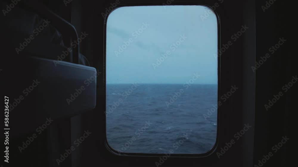 View from the porthole of the cabin to the stormy endless sea against the background of an overcast sky. Concept of a cruise and a sea trip View from the porthole of the cabin to the stormy endless sea against the background of an overcast sky. Concept of a cruise and a sea trip