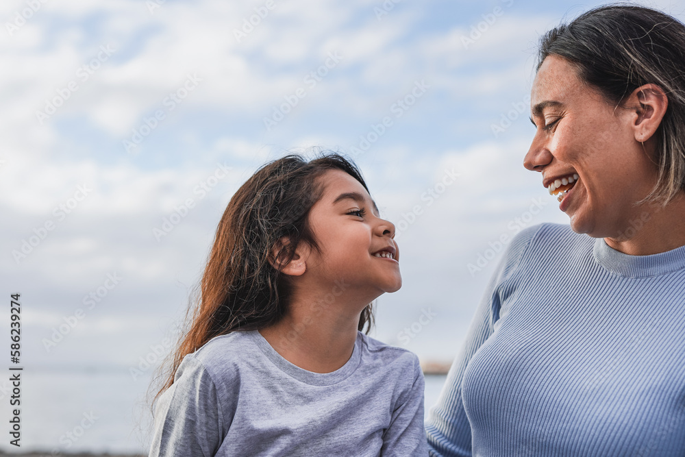 Happy latin mother and little daughter having fun together on the beach - Mom and child love - Family concept Happy latin mother and little daughter having fun together on the beach - Mom and child love - Family concept