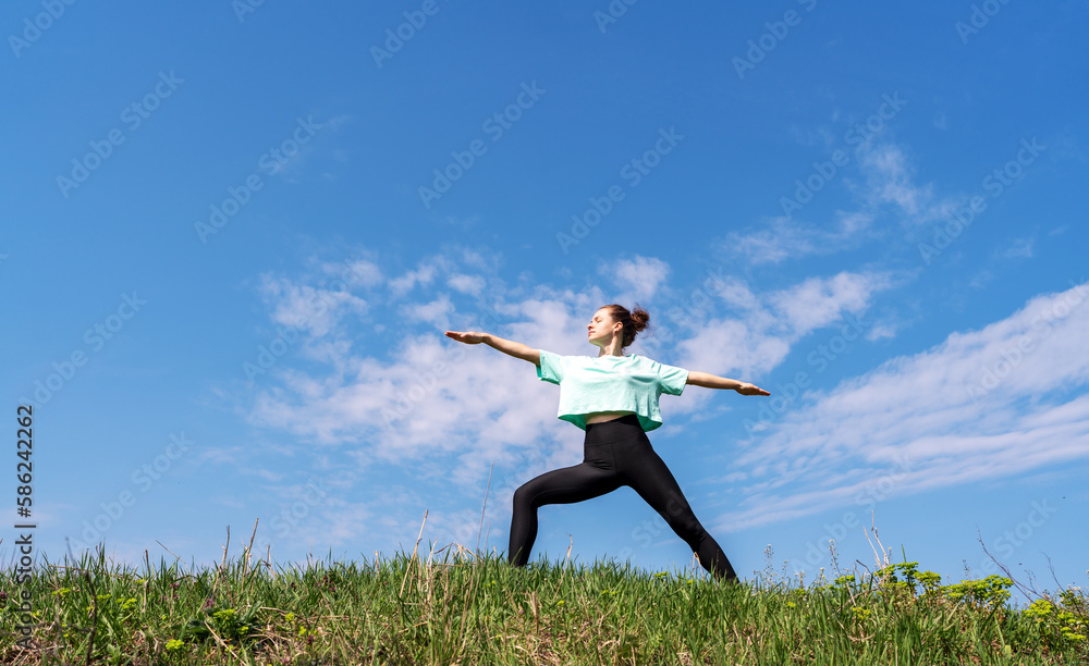 Fitness woman doing yoga against blue sky outdoors. Fitness woman doing yoga against blue sky outdoors.