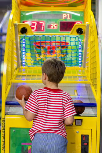 Entertainment center and children's area with slot machines. boy throws basketball in basket. Basketball arcade game.