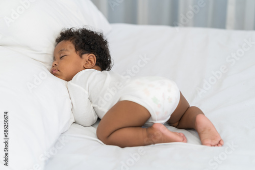 black african american baby sleeping on a white mattress.
