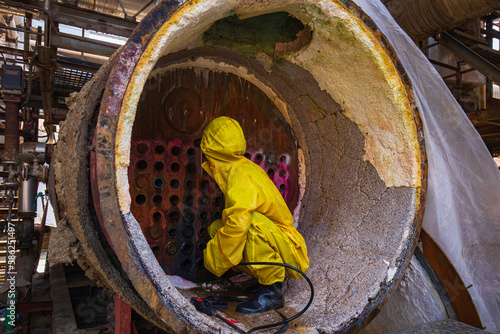 Male workers use high-pressure water jets to clean splashing the dirt of tube boilers in industrial areas or toxic hazardous material sulfur