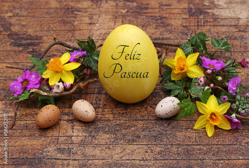 Feliz tarjeta de felicitación de Pascua: Huevo de Pascua con letras con el texto Feliz Pascua en madera rústica con narcisos y ramitas photo