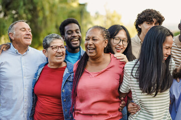 Happy multi generational people having fun together at city park while hugging each other - Multiracial friends concept