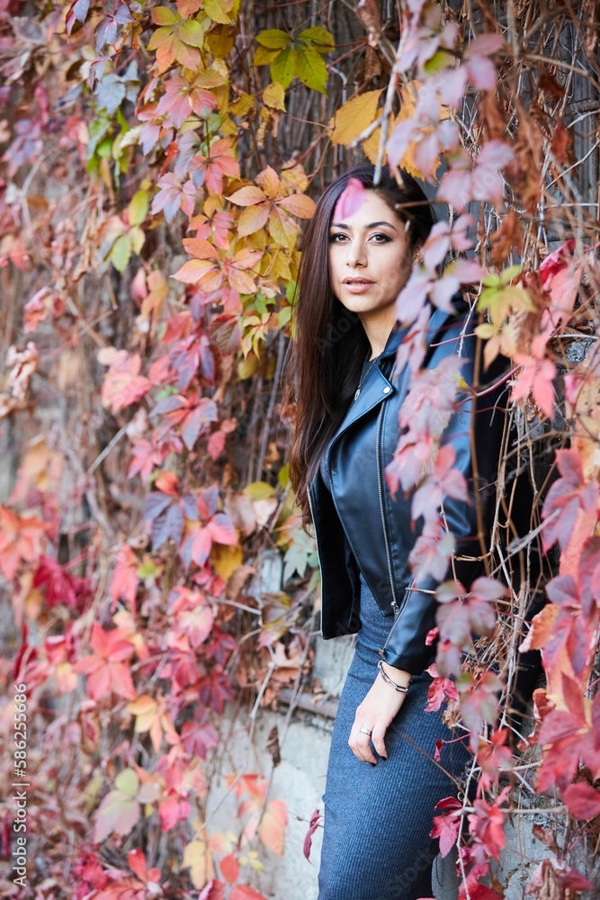A girl in a leather jacket and stylish clothes against the background of an old brick building, braided with a vine. The time of the year is autumn A girl in a leather jacket and stylish clothes against the background of an old brick building, braided with a vine. The time of the year is autumn