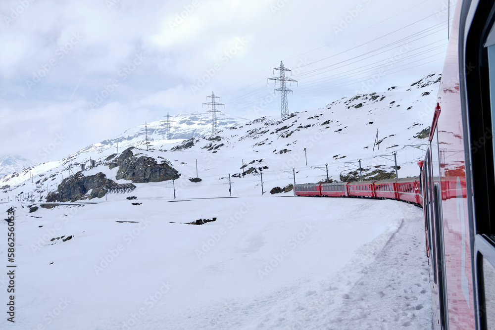 Bernina mountain pass. The famous red train is crossing the white lake. Amazing landscape of the Switzerland land. Famous destination and tourists attraction Bernina mountain pass. The famous red train is crossing the white lake. Amazing landscape of the Switzerland land. Famous destination and tourists attraction