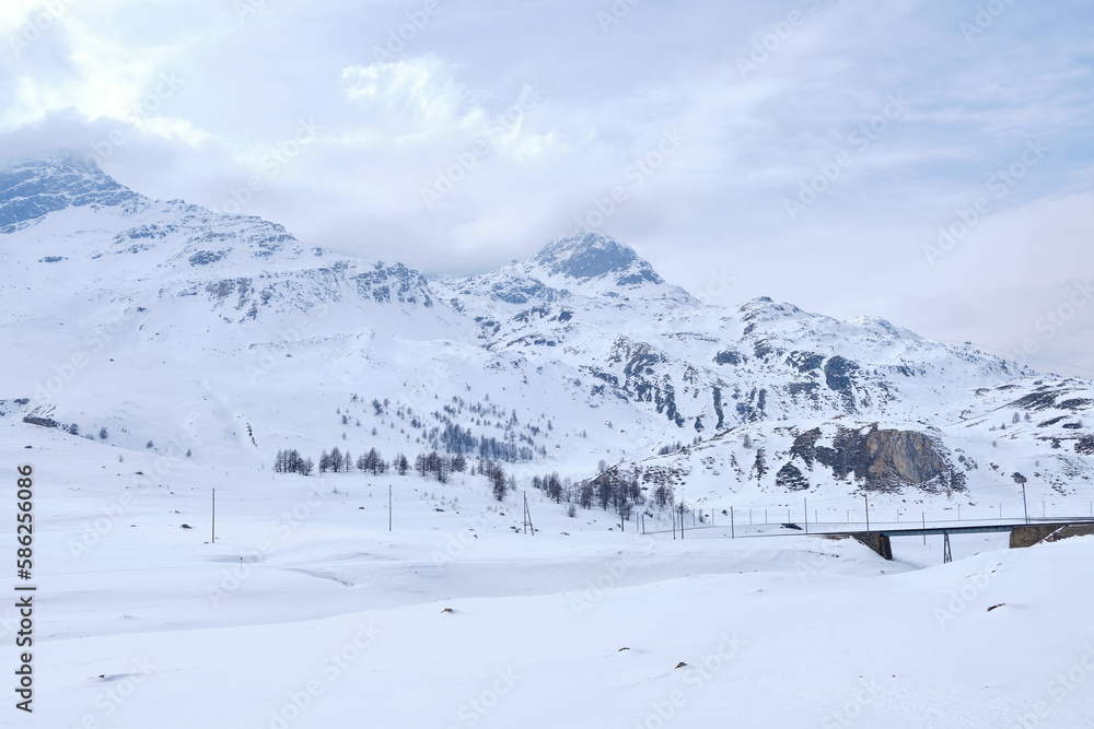 Bernina mountain pass. The famous red train is crossing the white lake. Amazing landscape of the Switzerland land. Famous destination and tourists attraction