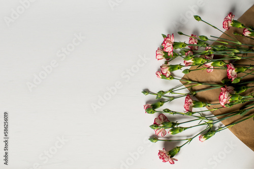 Fresh white carnation flowers with red edges on white table background. Empty...