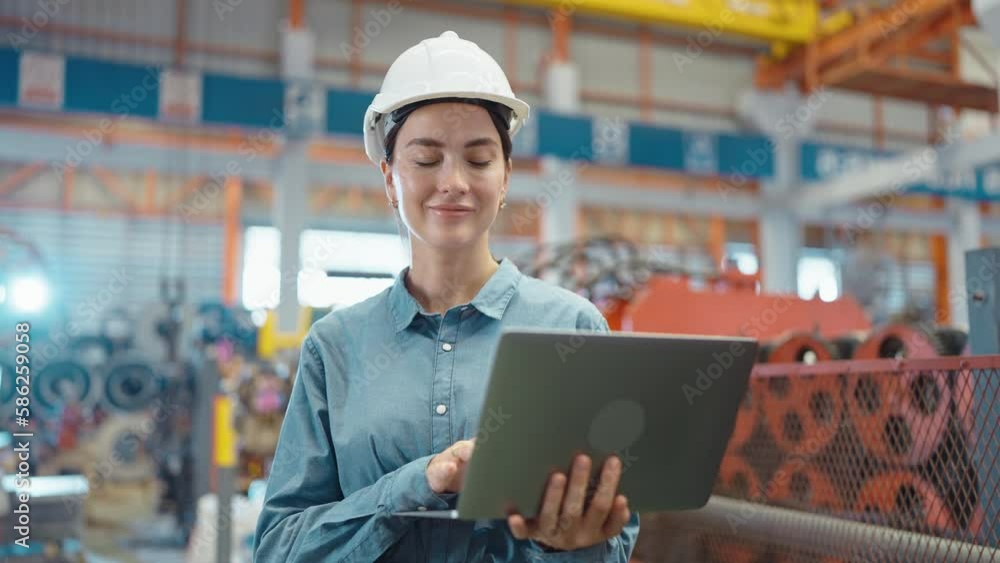 Close up smiling face of engineer manager leader woman wearing helmet holding laptop looking at camera at manufacturing factory Close up smiling face of engineer manager leader woman wearing helmet holding laptop looking at camera at manufacturing factory