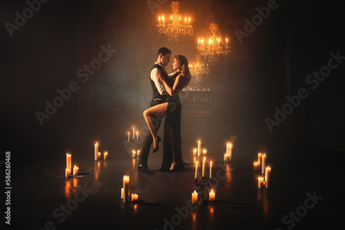 Silhouette shadow sexy couple man and blonde woman dancing. Gothic Girl dancer in Black evening dress embracing guy. Portrait Fashion model suit. dark room full smoke fantasy scenery candles burning