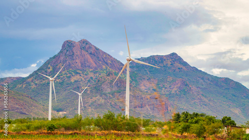 Windmill - Wind turbine below the mountain on the agriculture land. Alternate energy source generator with environment friendly. Wind turbines for ecological power supply ..