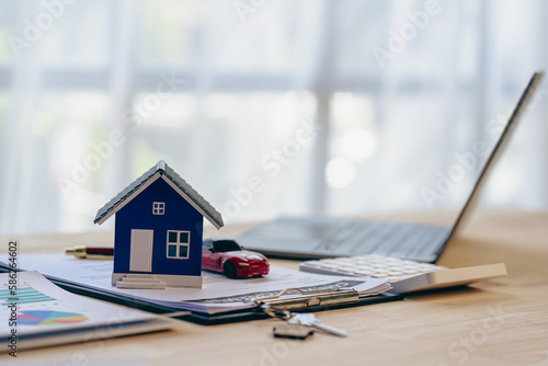 House model and car, laptop contract document on table, real estate business concept