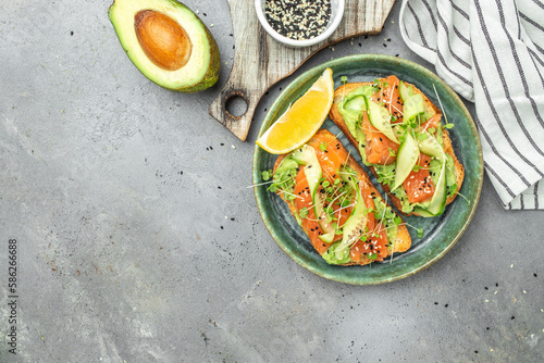 sandwich with cream cheese, salmon, avocado, cucumber, tomato and greens on a light background. Keto breakfast or brunch. banner, menu, recipe place for text, top view