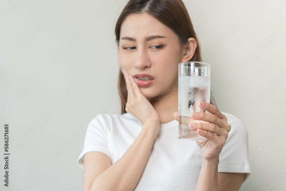 Suffering from toothache, asian young woman, girl touch cheek, face expression ache or feel pain, sensitive molar teeth, hand holding glass of water with ice, inflammation when drink cold, healthcare. Suffering from toothache, asian young woman, girl touch cheek, face expression ache or feel pain, sensitive molar teeth, hand holding glass of water with ice, inflammation when drink cold, healthcare.