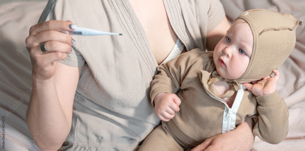 Mom measures body temperature baby by electronic thermometer. Sick child with high temperature. Children illness, clod and flue, runny nose, cough, disease, parent care Mom measures body temperature baby by electronic thermometer. Sick child with high temperature. Children illness, clod and flue, runny nose, cough, disease, parent care