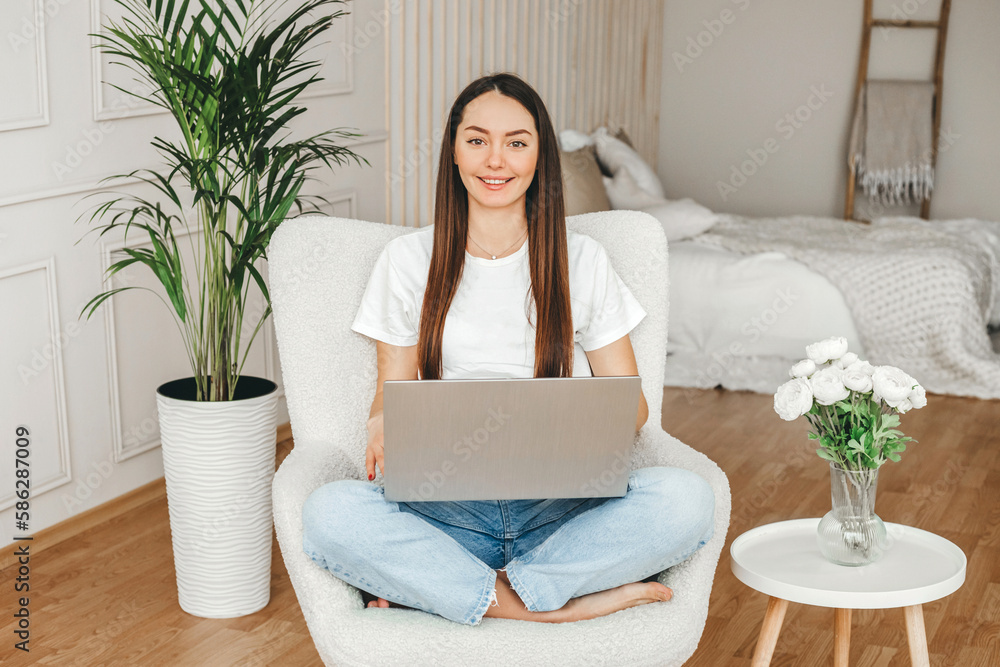 A girl with a laptop sits on a chair, looks at the camera and smiles A girl with a laptop sits on a chair, looks at the camera and smiles