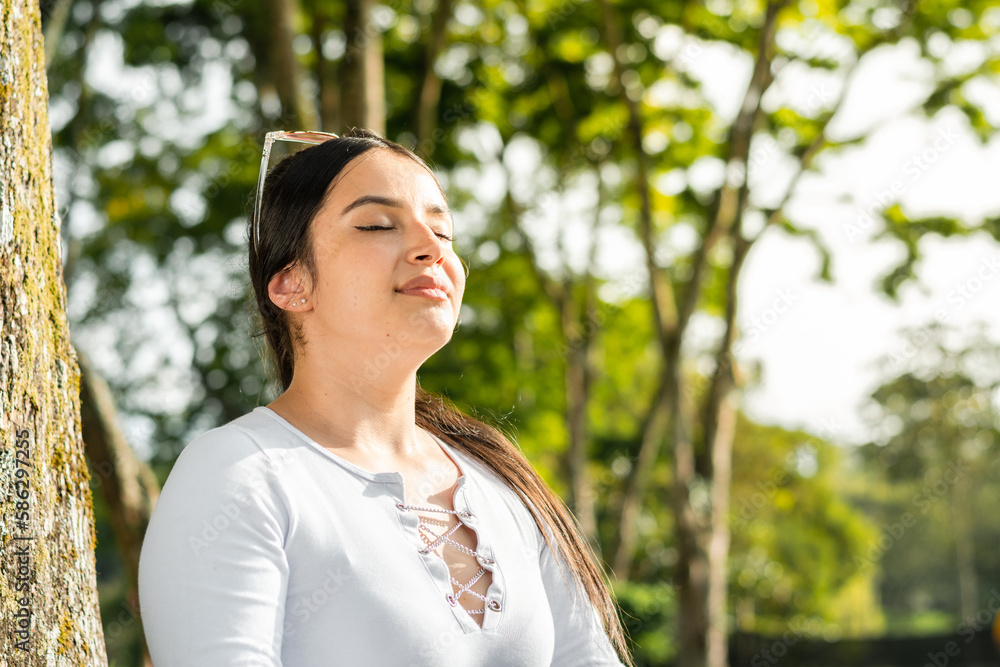 portrait of beautiful latin woman, with her eyes closed and raising her head to breathe the pure air of nature.