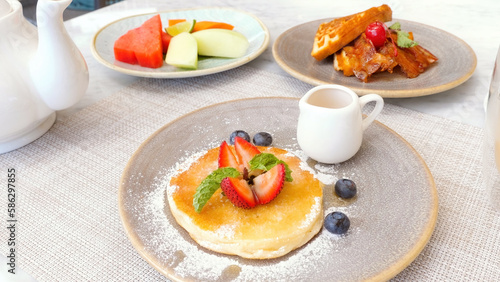 Delicious sweet food. Fresh pancake with berries, waffles and fruits on the table in cafe. Sugar, non health food concept.